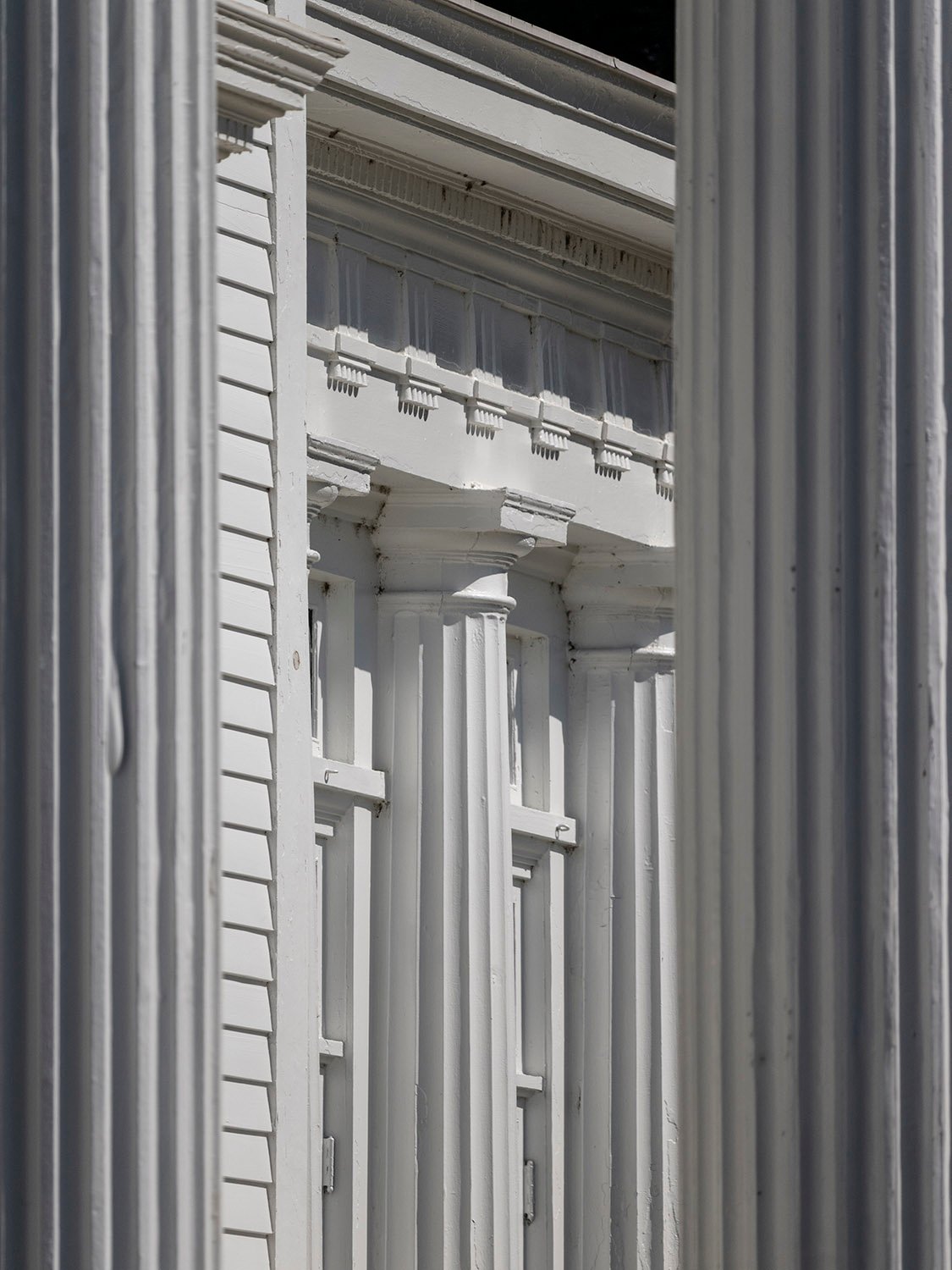 Looking between columns at the enclosed porch on the John Blackmar Residence, Columbus, Georgia