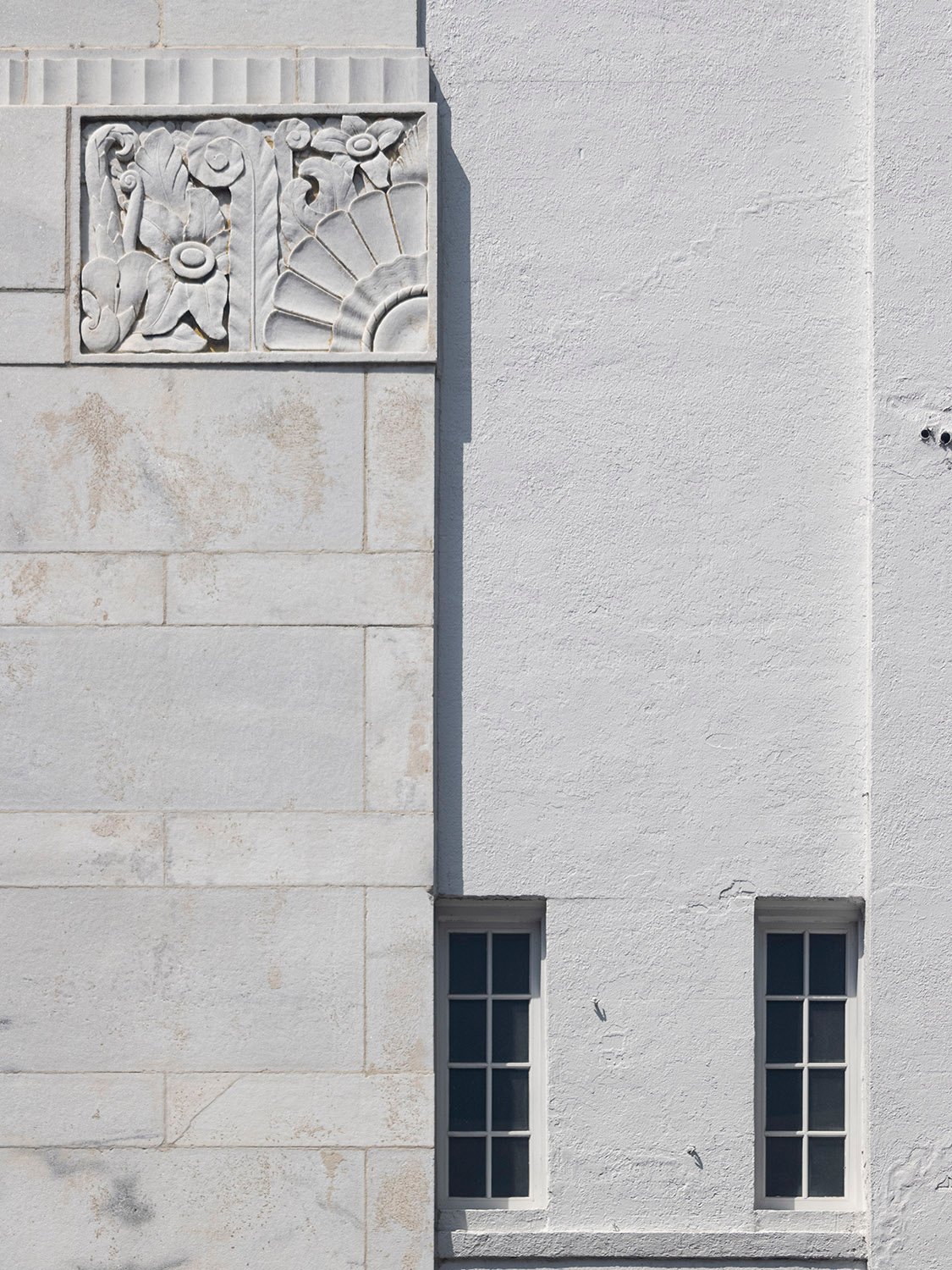 Marble block, bas-relief ornamentation, stucco facing, and second-floor windows on the east elevation of the Strand Theatre, Marietta, Georgia